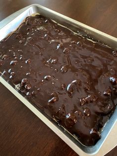 a pan filled with chocolate cake sitting on top of a wooden table