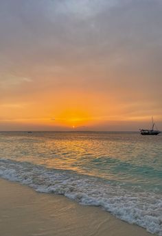 the sun is setting over the ocean with a boat in the distance on the water