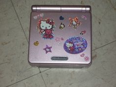 a pink hello kitty laptop with lots of stickers on the front and back cover