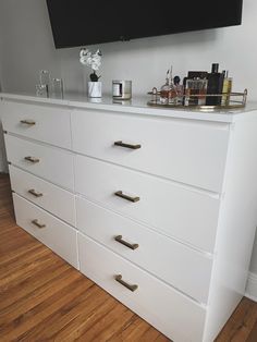 a large white dresser with gold handles and drawers in a room that has hardwood floors