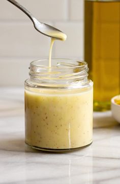 a spoon is pouring honey into a jar