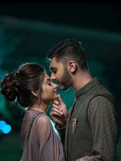 a man and woman standing next to each other in front of a stage with lights