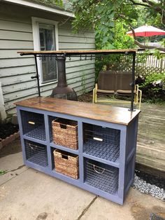 an outdoor kitchen made out of old cabinets with baskets on the top and shelves below