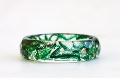 "Crafted with care, this nature-inspired resin band features a beautiful emerald green color that evokes images of lush forests and woodland glades. The faceted design adds texture and dimension to the ring, making it a truly unique and eye-catching piece. The ring is designed to be comfortable to wear, with a smooth finish and a perfect fit. If you choose the \"without flakes\" option for the Faceted Moss Ring, the ring will be made without any metal flakes added to the resin. This means that the ring will be completely hypoallergenic, making it a great choice for anyone with sensitive skin or allergies to metal. Rest assured that even without the metal flakes, the ring will still be a stunning and unique piece of nature-inspired jewelry that you'll love wearing. Width: 5 mm/0.19 in Thick Emerald Green Ring, Moss Ring, Faceted Design, Emerald Green Color, Green Ring, Ring Making, Green Rings, Nature Inspired Jewelry, Yes To The Dress