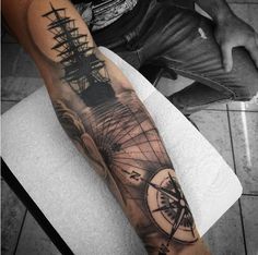 a man's arm with a ship and compass tattoo on it