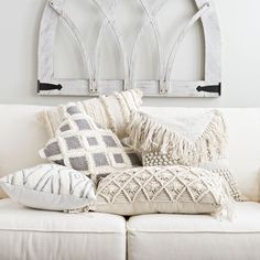 a white couch topped with lots of pillows next to a wall mounted coat hanger