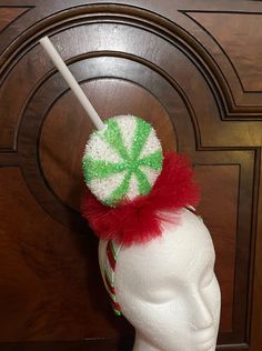 a white mannequin head with a green and red candy cane on it's top