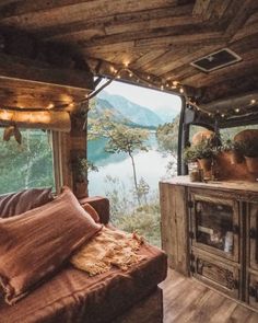 a living area with a couch, table and window looking out onto a lake in the distance