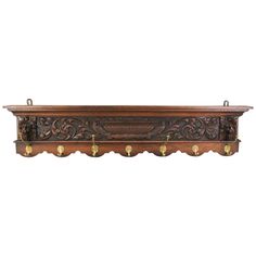 an ornate wooden shelf with brass handles and knobs on the top, against a white background