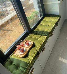 two trays filled with drinks sitting on top of a window sill next to a green cushion