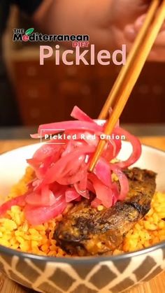 a bowl filled with rice and meat next to chopsticks on top of it