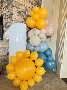 balloons are arranged on the floor in front of a brick wall and stone fireplace,