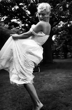 an old photo of a woman in a dress on the grass with her leg up