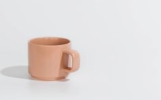 a pink coffee cup sitting on top of a white table