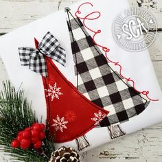 a christmas tree on top of a white table cloth with red berries and pine cones