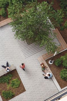 an overhead view of people sitting on benches in a park with trees and shrubs surrounding them