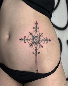 a cross tattoo on the side of a woman's stomach