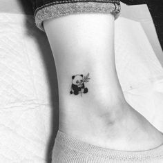 a small panda bear tattoo on the side of a woman's right leg and ankle