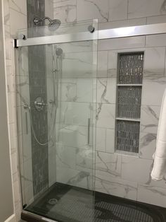 a walk in shower sitting next to a white tiled wall and floor with glass doors