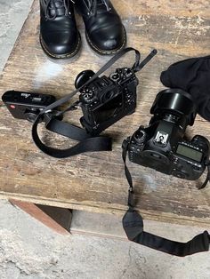 a camera and some other items on a wooden table next to a pair of black shoes