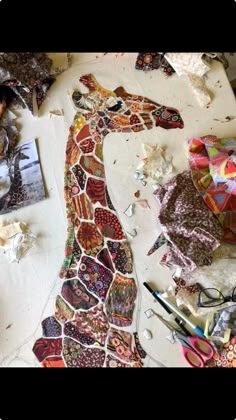 the giraffe is made out of many different fabrics and fabric pieces on the table