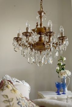 a chandelier hanging from the ceiling in a room with white walls and furniture