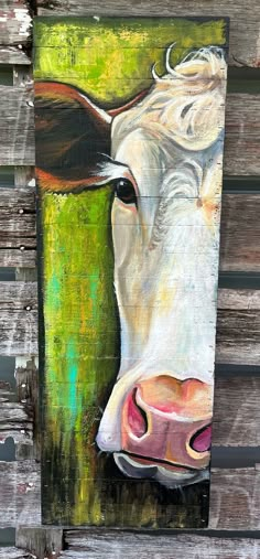 a painting of a cow is shown on a wooden fence with green grass in the background