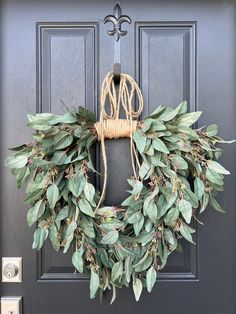 a wreath is hanging on the front door with greenery and burlock around it