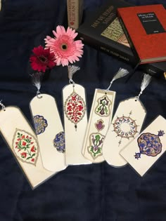 five bookmarks with designs on them sitting next to a pink flower