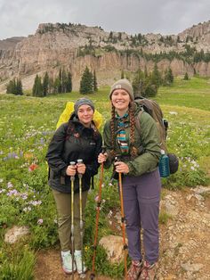 two women with backpacks and hiking poles posing for the camera