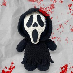 a crocheted black and white stuffed animal with a hood on it's face