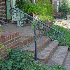 a set of stairs leading up to the front door of a brick house with potted plants on either side