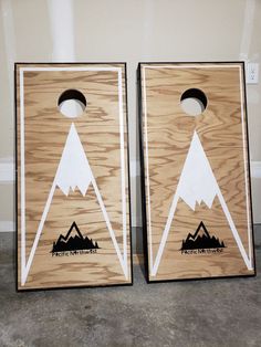 two wooden cornhole boards with mountains on them