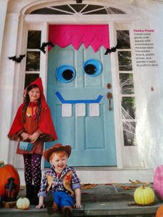 two children dressed up in costumes standing next to a door decorated with fake faces and bats