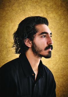 a man with long hair and a beard looks off to the side while wearing a black shirt