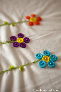 three colorful buttons are attached to a string on a white sheet with green and yellow beads