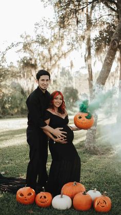 a pregnant couple posing with pumpkins in the grass