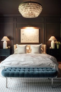 a bedroom with a large bed and chandelier hanging from it's ceiling