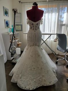 a wedding dress on display in front of a window