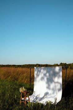 a white sheet draped over a chair in the middle of a field