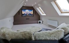 a living room with a couch, television and windows in the roof top dormer