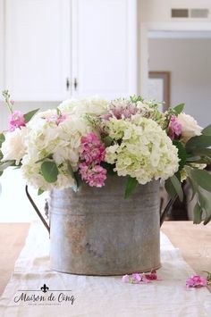 a bucket filled with flowers on top of a table