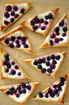 blueberries and cream cheese pizza slices are arranged on a sheet of parchment paper, ready to be eaten