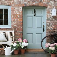 a bicycle parked in front of a blue door with flowers on the ground next to it