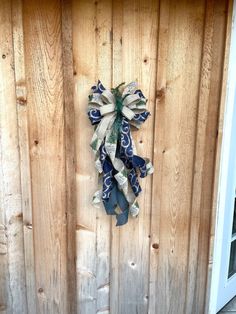 a blue and white bow hanging on the side of a wooden door