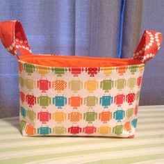 a colorful bag sitting on top of a bed next to a blue curtain and window