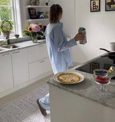 a woman standing in a kitchen holding a can