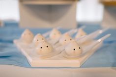 small plastic white cats sitting on top of a blue and white tablecloth covered table