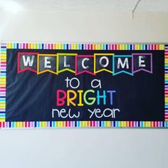 a welcome sign hanging on the wall in front of a white wall with colorful stripes