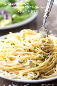 a fork is being used to eat spaghetti on a plate with parmesan cheese